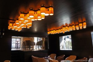 bespoke ceiling lights in maple wood in basement above tables for a wine bar in gent
